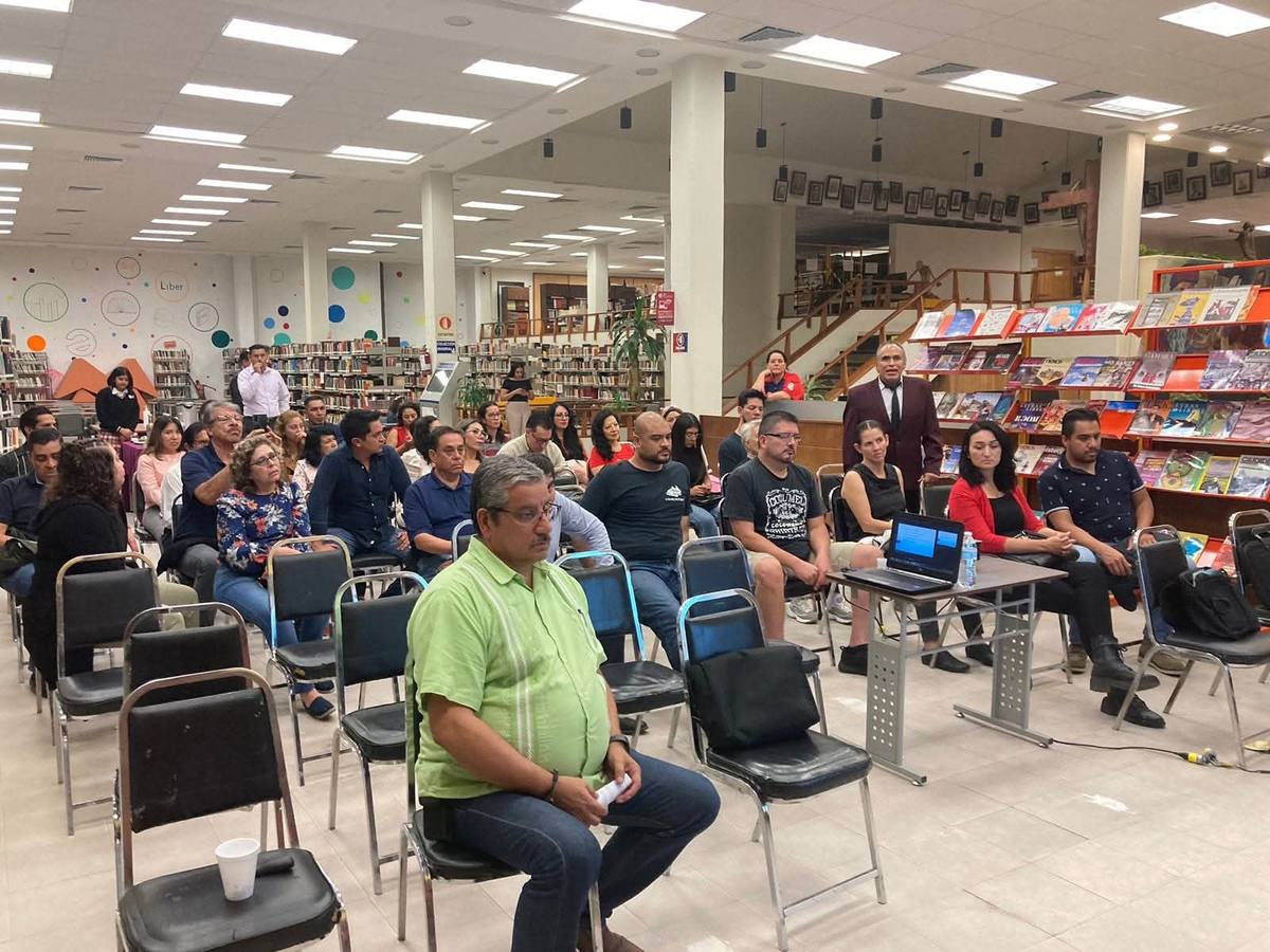 Asistentes participando en una conferencia en una biblioteca