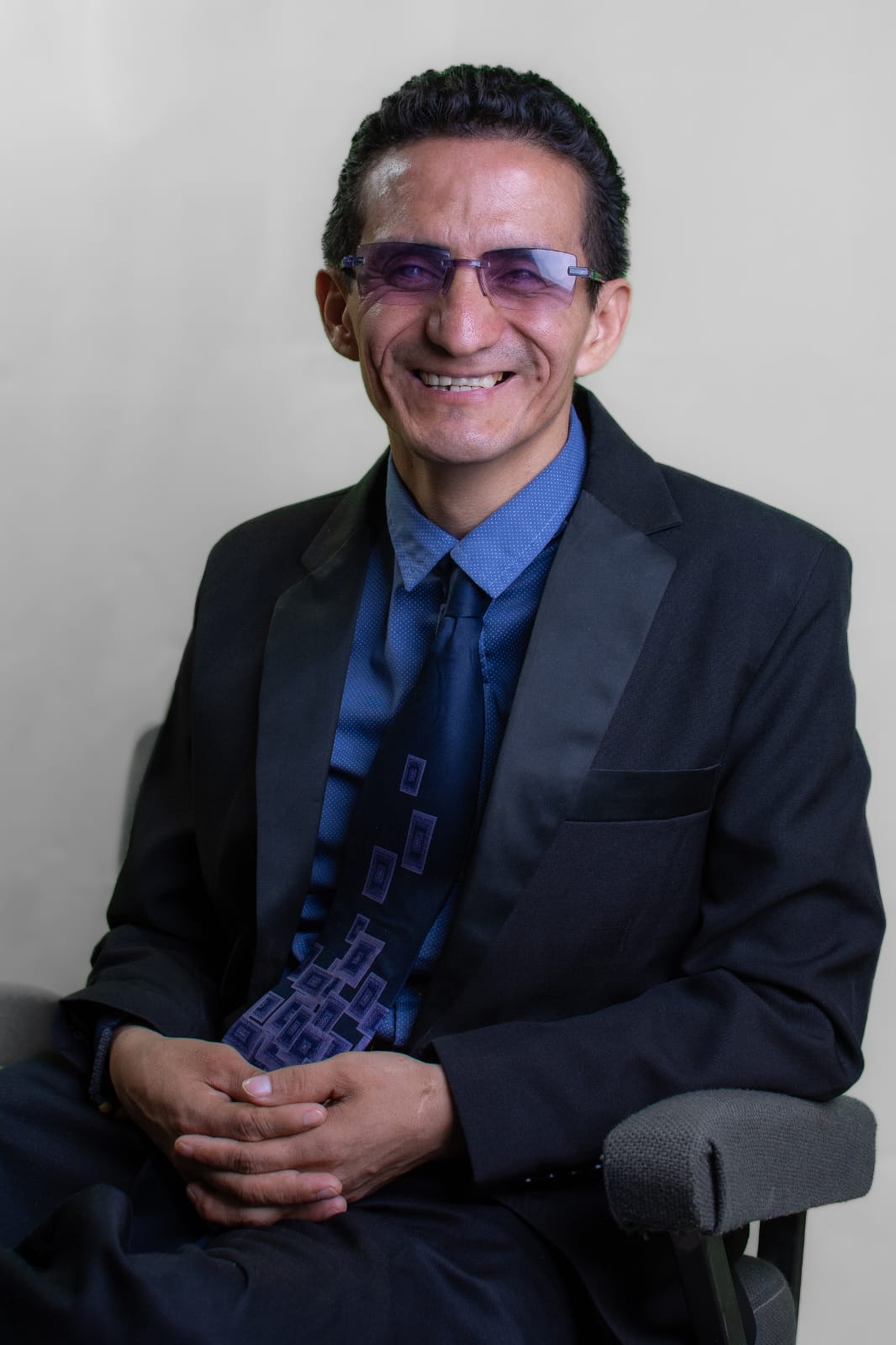 Franko Kaiser sentado, sonriendo, con traje oscuro y corbata azul